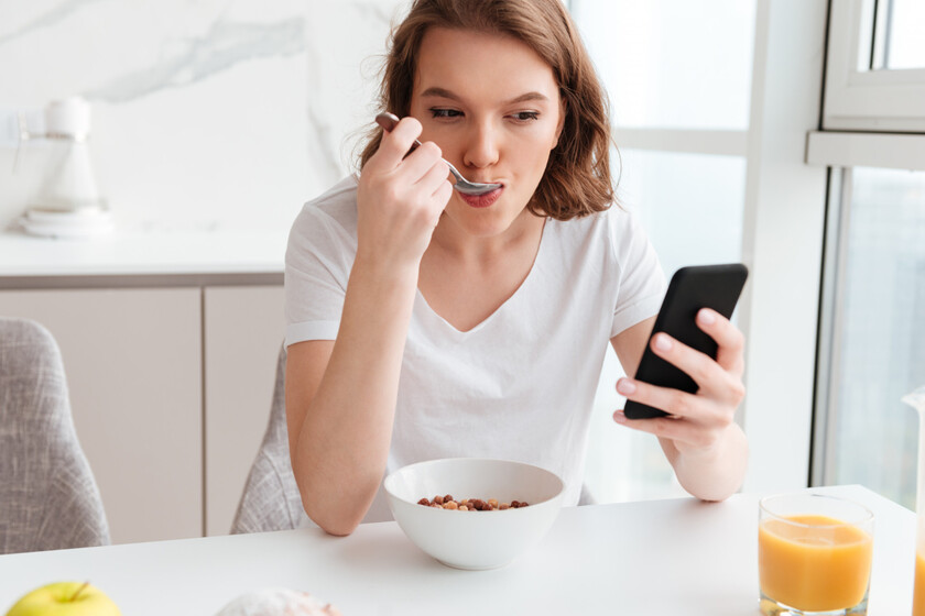 Creíamos que comer con el móvil en la mano era inofensivo. La ciencia avisa de que está "hackeando" nuestra saciedad